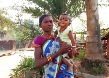 Chandrika Majhi holds her baby son outside her house in Gadadi, India.